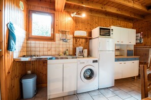 Una cocina compacta equipada con lavadora, microondas y lavabo.