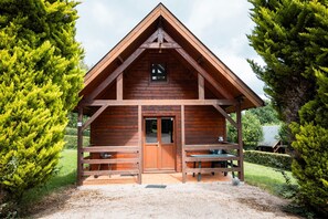 Eine Holzhütte mit Satteldach, einer Haustür und einer kleinen Veranda mit Bänken.