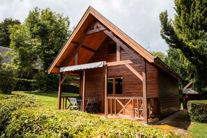 Une cabane en bois avec un toit en pente, une véranda avec des chaises et une petite table.