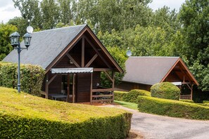 En stuga av trä med ett sluttande tak, en veranda med sittplatser och en satellantenn.