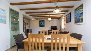 Een eethoek met een houten tafel en stoelen, een groen kastje en kunstwerken aan de muur.