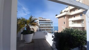 A balcony with a potted plant, a view of a multi-story building, and a clear sky. - Sea View Suite Eventi Felici Apartment with Terrace, Wi-Fi and Air Conditioning (Bari)