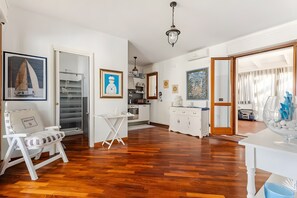 Un vaste espace de vie doté d’un plancher en bois, d’une table à manger, d’une cuisine et d’une grande fenêtre.