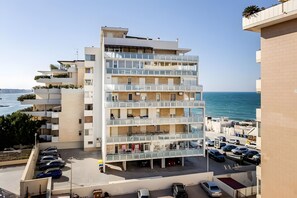A multi-story hotel with balconies, a parking area, and a view of the sea. - ‘Sea View Suite Eventi Felici’ Apartment with Terrace, Sea View, Wi-Fi & Air Conditioning (Bari)