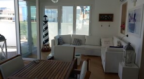 Un salon moderne avec un canapé, une table en bois, une lampe et une vue à travers des portes vitrées.