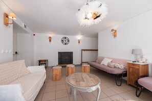 A modern living room with a sofa, a round coffee table, a TV, and decorative wall sconces.
