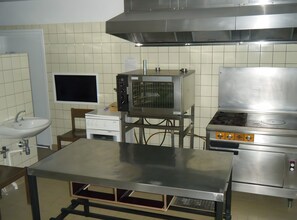 A kitchen with a stainless steel sink, a microwave, a stove, and a tiled backsplash. - Gîte l'Evasion, 20 to 35 Guests (Bussang)