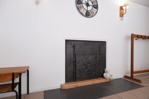 A room with a fireplace, a clock, and a coat rack.