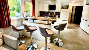 Een moderne keuken met een centraal eiland, barstoelen en een televisie boven het eiland.