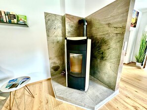 Een moderne kamer met een ingebouwde houtkachel, een klein tafeltje met tijdschriften en een plant.