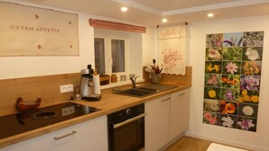 A kitchen with a wooden countertop, a coffee machine, a sink, and a wall-mounted oven. - Holiday Home “La Maison De Mediovilla” with Private Terrace, Garden & Wi-Fi (Wingersheim les Quatre Bans)