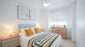 Une chambre à coucher comprenant un lit, des tables de chevet, une commode et un ventilateur de plafond.