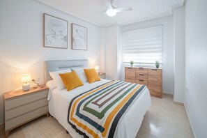 Ein Schlafzimmer mit Bett, Nachttischen, Kommode und Deckenventilator.