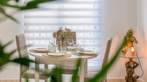 Une table à manger dressée avec des assiettes, des verres et un vase de fleurs.