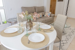 Een ronde eettafel gedekt met borden, glazen en een vaas met bloemen.