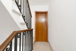 Een trap met een houten leuning en zwarte spijbels die naar een houten deur leidt.