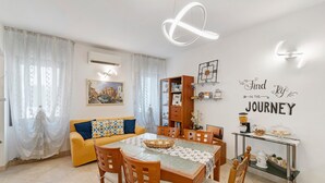 A dining area with a table, chairs, a glass coffee table, a wall-mounted shelf, and a wall decoration. - Camera Mare - Casa Del Capitano, with Wi-Fi and Air Conditioning (Chioggia)
