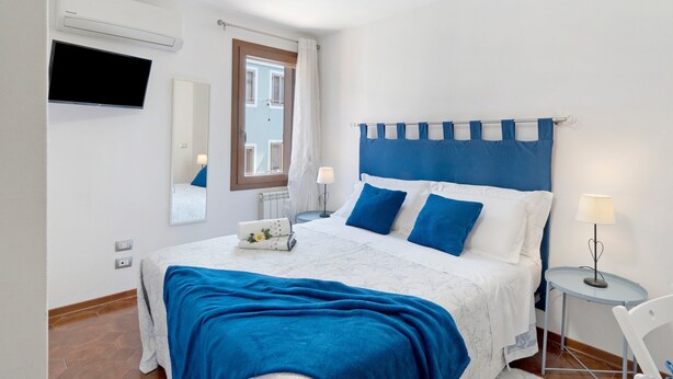 A bedroom with a bed, a TV, a window, and a bedside table. - Camera Mare - Casa Del Capitano, with Wi-Fi and Air Conditioning (Chioggia)