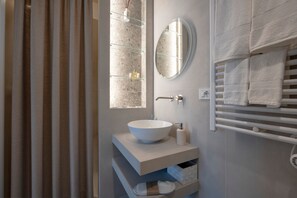 Un baño moderno con un espejo grande, un lavabo tipo recipiente y un perchero para toallas.