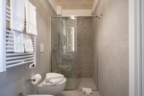 A modern bathroom with a glass shower enclosure, a toilet, and a towel rack with towels. - Studio Apartment 'Dimora Sofia, Charming House' with Wi-Fi and Air Conditioning (Savelletri)