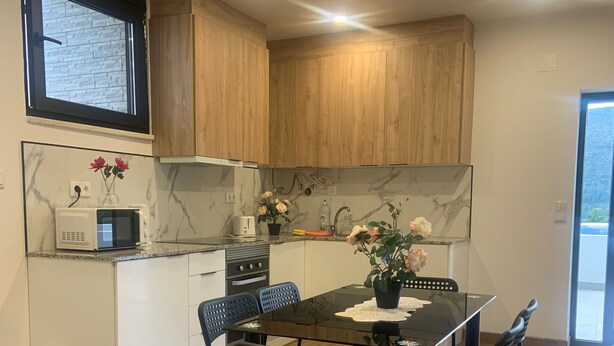 A modern kitchen with wooden cabinets, a microwave, and a dining table with chairs.
