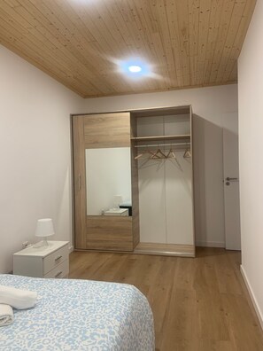 Un dormitorio con cama, mesita de noche, armario y espejo.