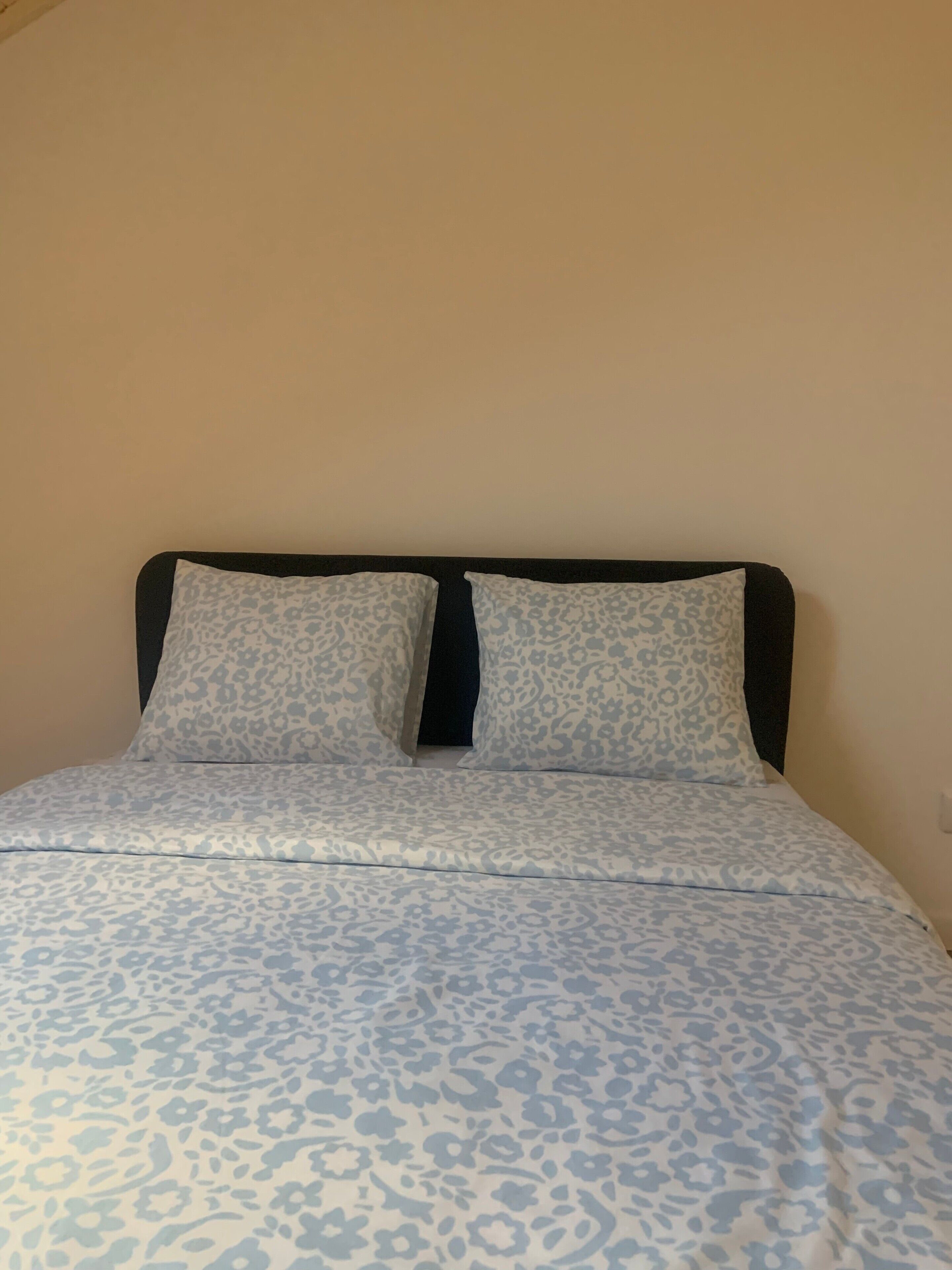 A bed with a patterned bedspread and two pillows with a leopard print design.