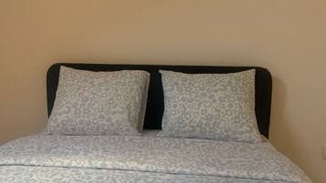A bed with a patterned bedspread and two pillows with a leopard print design.