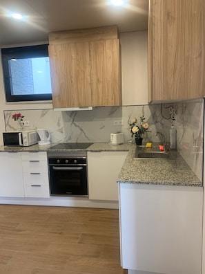A modern kitchen with wooden cabinets, a built-in oven, a microwave, and a sink. - House Near Mira de Aire Caves – Spacious and Family-Friendly (Mira de Aire)