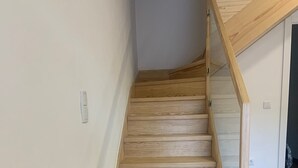 A wooden staircase with a handrail leading to an upper level.