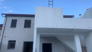 A modern building with a flat roof, a visible staircase, and a door leading to an entrance.