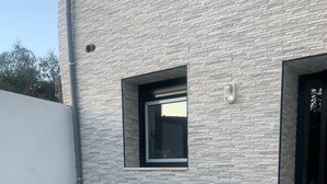 A modern building with a stone facade, a small window, and a door.