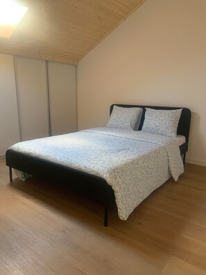 A single bed with a patterned bedspread and two pillows, a wooden floor, and a slanted ceiling. - House Near Mira de Aire Caves – Spacious and Family-Friendly (Mira de Aire)