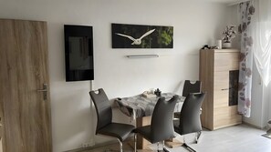 Un espace repas comprenant une table, des chaises, un buffet et une œuvre d’art accrochée au mur.