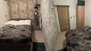 Ein Schlafzimmer mit einem Bett, einem Holzschrank, einer kleinen Ablagefläche mit einer Pflanze und einem Fernseher auf dem Schrank.
