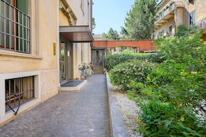Un étroit sentier pavé de pierres menant à un bâtiment doté d’une porte et où un vélo est garé à l’extérieur.