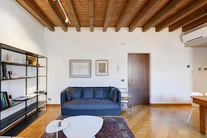 Un salon avec un canapé, une table basse, une bibliothèque et une porte.