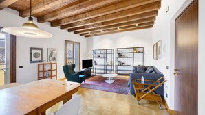 Een ruime woonkamer met een houten plafond, een grote tafel, een bank en een televisie.