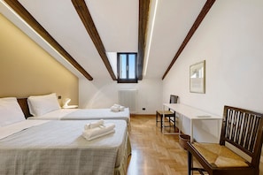 Une chambre avec deux lits, une petite table, une chaise, un radiateur et une fenêtre.