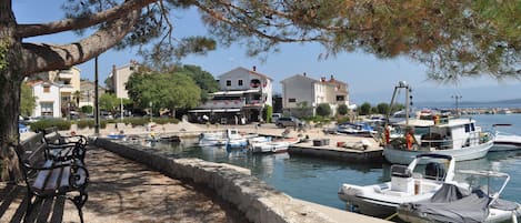 A marina with boats docked, a bench, and buildings in the background.