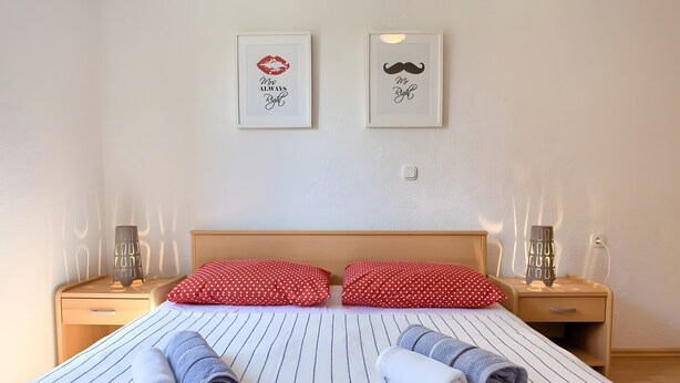 A hotel room with a bed, two pillows, two bedside tables, and two wall-mounted light fixtures. - Apartment 'Daniela with Sea View' with Sea View, Wi-Fi and Air Conditioning (Porat)
