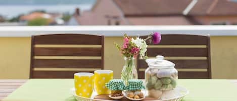 A table with yellow cups, a vase with flowers, and a jar of cookies on a tray.