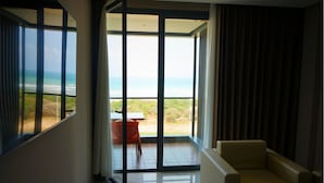 Una habitación con un amplio ventanal corredero que da a un balcón con vistas a la playa.