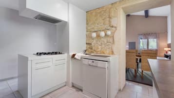 Eine moderne Küche mit weißen Schränken, einem eingebauten Backofen und einer Wand mit Steinverkleidung.
