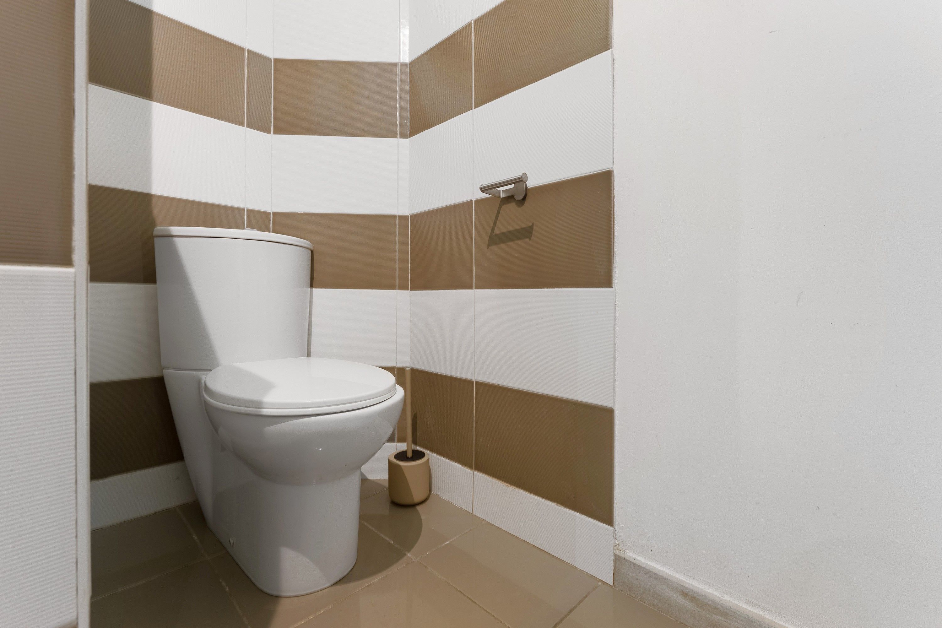 Une salle de bain standard équipée de toilettes, d’un bidet et d’un porte-rouleau de papier toilette.