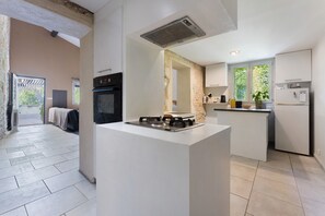A modern kitchen with a central island, built-in oven, and a refrigerator.