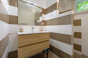 A bathroom with a mirror, sink, and wooden vanity.