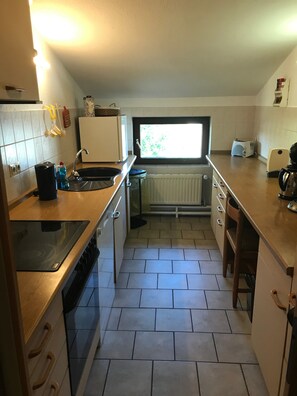 Eine kompakte Küche mit Einbauherd, Spüle und einem Fenster für natürliches Licht.