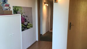 A hallway with a white cabinet, a wall-mounted picture, a wooden door, and a light fixture.