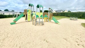 A playground with slides and climbing structures on sandy ground. - Mobile Home – 6 Guests with Shared Pool, Terrace, and Garden (Erdeven)